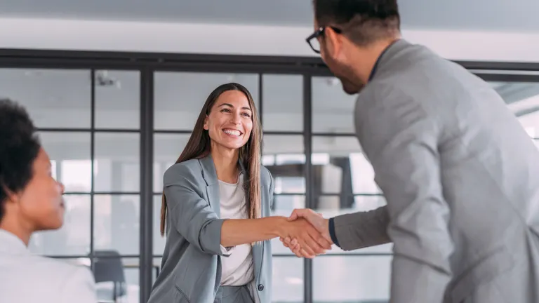 Two people shaking hands in an office.